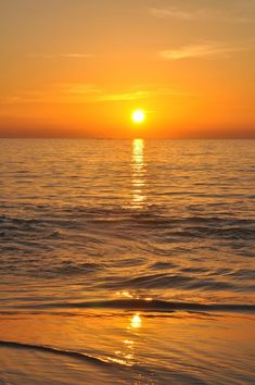 the sun is setting over the water at the beach