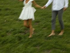 a man and woman are holding hands in the grass