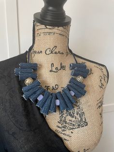 a mannequin wearing a black top with blue tassels on it's neck