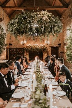 a group of people sitting at a long table with plates and wine glasses on it