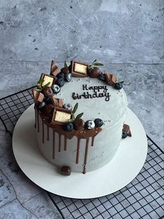 a birthday cake with chocolate icing and decorations on a cooling rack, ready to be eaten