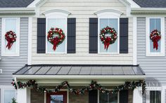 two wreaths are hung on the windows of a house decorated for christmas with red bows