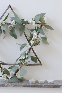 branches with white flowers and green leaves on them are arranged in the shape of an x