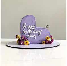 a purple heart shaped birthday cake with flowers