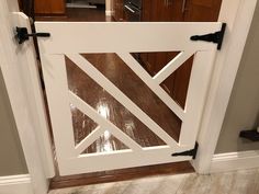 an open white door in a kitchen with wood flooring and wooden cabinets behind it