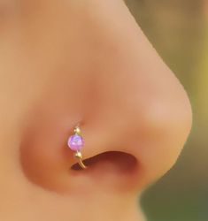 a close up view of the side of a person's nose with a pink ope piercing