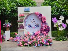 a clock surrounded by flowers and plants on display