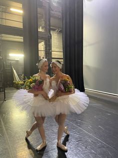 two women dressed in white tutus and holding bouquets