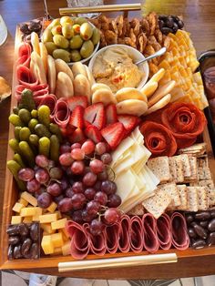 a platter filled with different types of cheeses, crackers, and fruit