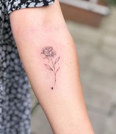 a woman's arm with a single rose tattoo on the left side of her arm