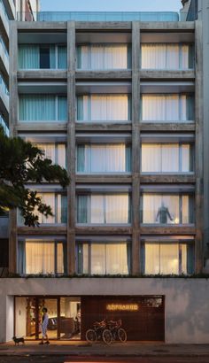 an apartment building with lots of windows and bicycles parked in the street outside at night