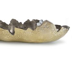 a gold and silver bowl with mountains on it's sides, sitting on a white surface