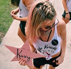 two girls are standing on the sidewalk holding signs