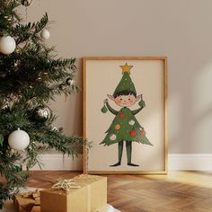 a christmas tree with presents under it next to a framed poster on the wall in a room