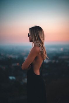 a woman standing on top of a hill looking at the city