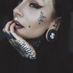 a woman with tattoos and piercings on her face