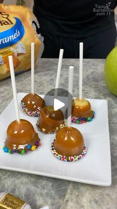 caramel apples with sprinkles on a white plate next to an apple