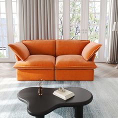 an orange couch sitting on top of a rug next to a coffee table