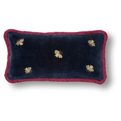 a blue and red velvet pillow with gold bees on the front, sitting on a white surface