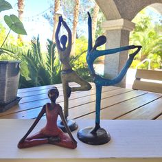 two figurines sitting on top of a wooden table next to plants and potted plants