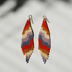 a pair of colorful beaded earrings hanging from a hook on a white background,