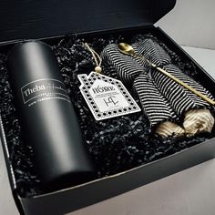 an open black box containing a bottle, scarf and hat with a tag on it