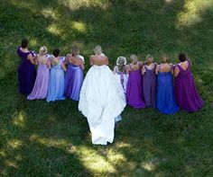 a bride and her bridal party standing in the grass with their backs to each other