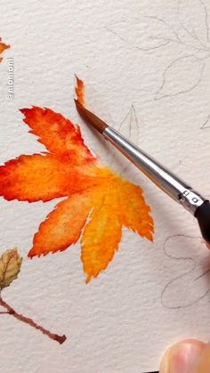 someone is painting leaves with watercolors on paper