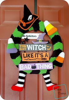 a knitted halloween wreath hanging on the front door to say witch like it's a bad thing