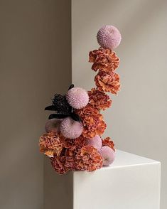 an arrangement of flowers on top of a white pedestal