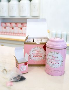 two pink boxes are sitting next to each other on the counter in front of some jars