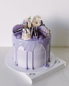 a purple cake with white frosting and sprinkles sitting on top of a book