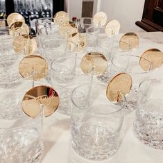 many glasses are lined up on a table with gold discs in them and the names of each glass