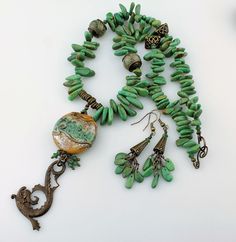 "This yummy new necklace is designed with my handmade lampwork glass bead in warm caramel brown and green, wire wrapped with a Vintaj antique brass sea serpent and jade green Swarovski crystals. The body of the necklace is genuine turquoise gemstones, antique brass, and 2 more lampwork beads. The clasp is an S hook and loop. You'll fall in love with this one of a kind lampwork and turquoise necklace! The necklace measures 20 1/2\" with a 3 3/4\" long pendant and the coordinating earrings measure Unique Turquoise Czech Glass Jewelry, Green Wire Wrapped Czech Glass Beaded Necklaces, Green Wire Wrapped Beaded Necklace With Czech Glass, Green Wire Wrapped Czech Glass Necklace, Handmade Turquoise Necklace In Czech Glass, Green Wire Wrapped Czech Glass Jewelry, Handmade Green Turquoise Dangle Necklace, Artisan Turquoise Necklace With Czech Glass, Artisan Wire Wrapped Czech Glass Necklaces