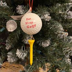 a golf ball ornament hanging from a christmas tree with the words eat sleep golf on it