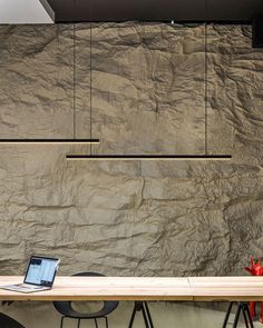 a laptop computer sitting on top of a wooden table in front of a stone wall