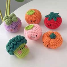 small crocheted fruits and vegetables sitting on a white table next to a plant