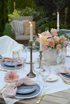 an outdoor table set with plates and place settings