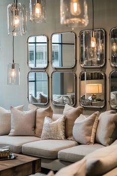 a living room filled with lots of furniture and mirrors on the wall above it's windows