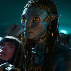 an alien woman with long hair and yellow eyes standing next to a man in costume