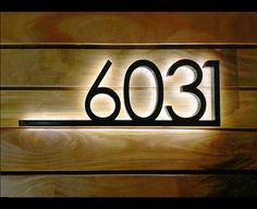 a wooden wall with a metal number sign on it's side and the number 6303 written in black