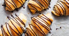 chocolate drizzled on croissants are sitting on a baking sheet