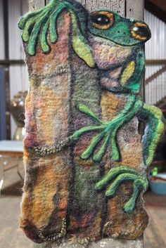 a close up of a piece of art on a pole with a frog painted on it