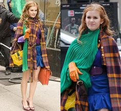 two women walking down the street, one wearing an orange and green coat while the other wears a blue dress