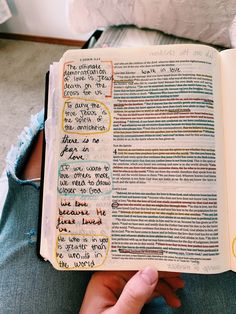 a person holding an open book with writing on the pages in different colors and sizes