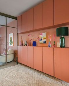 a living room with pink walls and lots of decor on the sideboard, along with a white rug