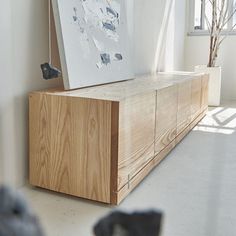 a large wooden cabinet sitting in the middle of a living room next to a window