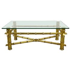 a glass and gold coffee table with bamboo accents on the bottom, against a white background