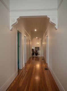 an empty hallway with hard wood flooring and white trim on the walls is seen in this image