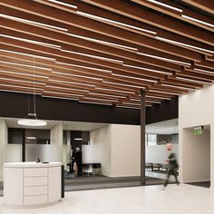 an office lobby with white counter tops and wooden beams on the ceiling, while a man walks by